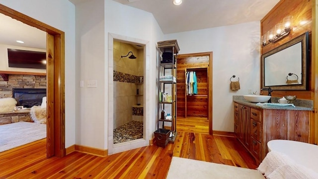 full bathroom featuring baseboards, a tile shower, wood finished floors, recessed lighting, and lofted ceiling