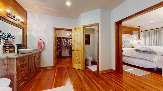 ensuite bathroom featuring toilet, hardwood / wood-style flooring, baseboards, vanity, and recessed lighting