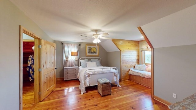 bedroom featuring light wood finished floors, vaulted ceiling, a ceiling fan, a spacious closet, and baseboards