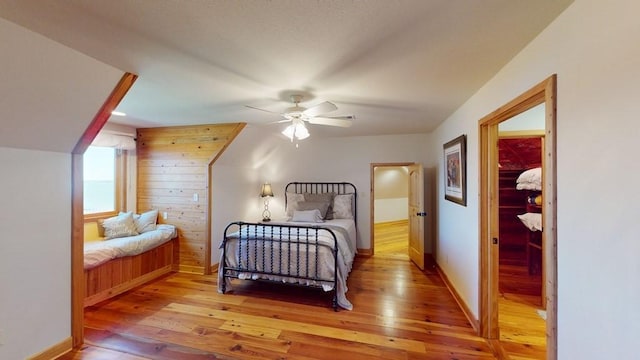 bedroom featuring light wood-type flooring, baseboards, and wood walls