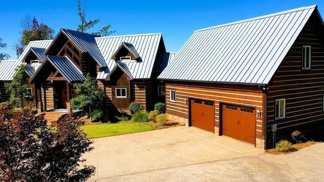 log cabin with a standing seam roof, driveway, metal roof, and an attached garage