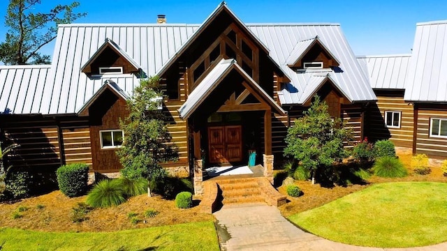 view of front of property with a standing seam roof, metal roof, stairs, and log exterior
