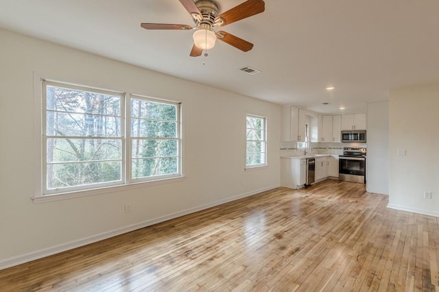 unfurnished living room with light hardwood / wood-style flooring and ceiling fan