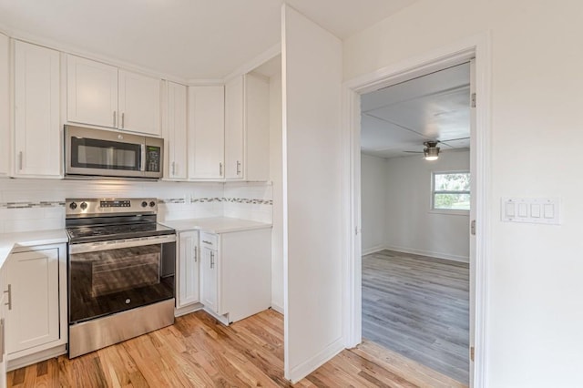 kitchen featuring ceiling fan, stainless steel appliances, light hardwood / wood-style floors, white cabinets, and decorative backsplash