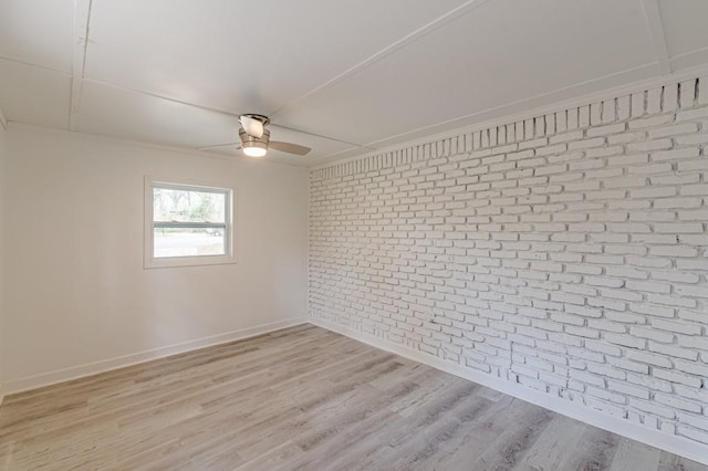 unfurnished room featuring ceiling fan, brick wall, and light hardwood / wood-style flooring