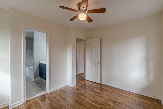 unfurnished bedroom featuring wood-type flooring, connected bathroom, and ceiling fan