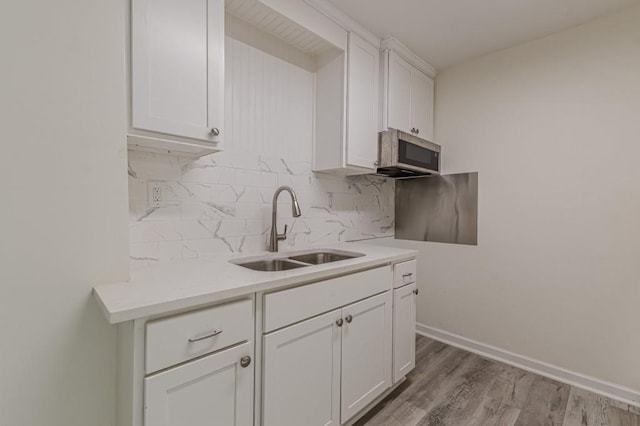 kitchen with white cabinetry, sink, tasteful backsplash, and hardwood / wood-style flooring