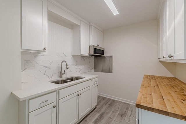 kitchen with tasteful backsplash, white cabinetry, and sink