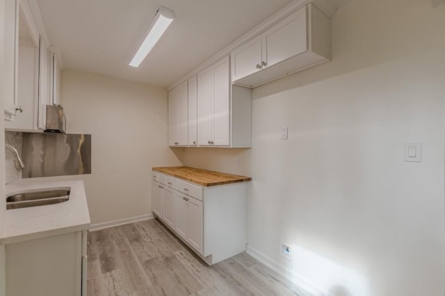 kitchen featuring butcher block counters, sink, light hardwood / wood-style flooring, and white cabinets