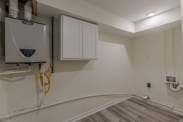 clothes washing area featuring cabinets, electric dryer hookup, washer hookup, light hardwood / wood-style floors, and water heater