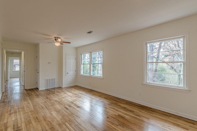 empty room with light hardwood / wood-style flooring, a wealth of natural light, and ceiling fan