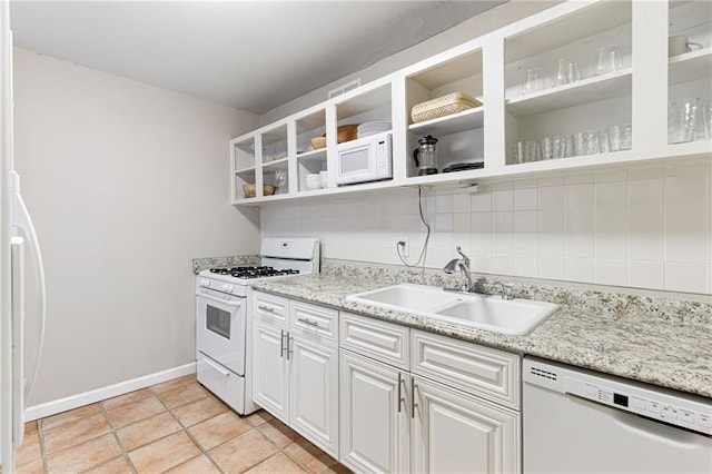 kitchen with white appliances, backsplash, sink, light tile patterned flooring, and white cabinetry