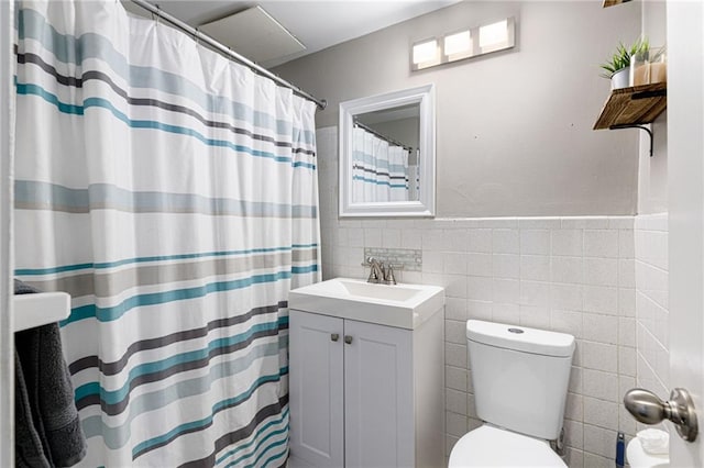 bathroom featuring vanity, curtained shower, toilet, and tile walls