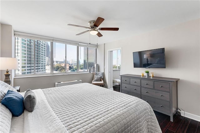 bedroom with dark hardwood / wood-style floors, ceiling fan, and an AC wall unit