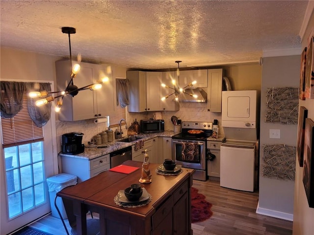 1625 Conley Rd Unit 229, Conley, GA 30288 - kitchen featuring stainless steel appliances, a chandelier, wall chimney range hood, estacked washer and dryer, and a textured ceiling
