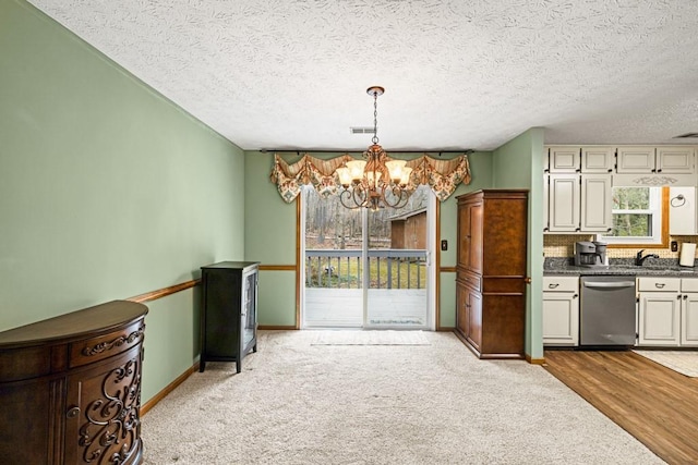 kitchen with a notable chandelier, visible vents, baseboards, dishwasher, and dark countertops