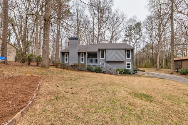 view of front of house with a chimney, a porch, and a front yard