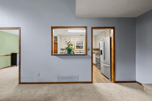 spare room featuring baseboards, visible vents, and light colored carpet