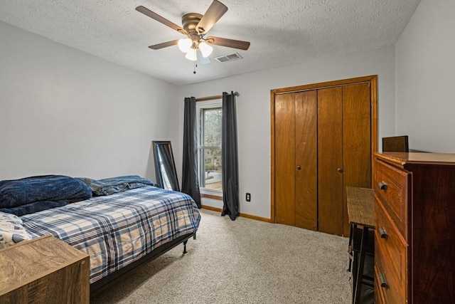 bedroom with a textured ceiling, light colored carpet, a ceiling fan, baseboards, and visible vents