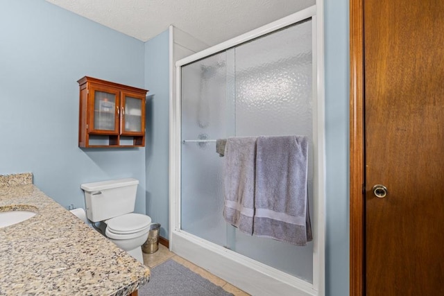 full bathroom featuring a stall shower, toilet, tile patterned floors, a textured ceiling, and vanity