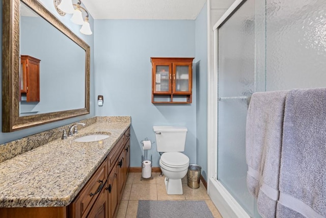 bathroom featuring tile patterned flooring, toilet, vanity, baseboards, and a shower stall