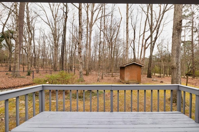 wooden deck featuring an outbuilding, a shed, and fence