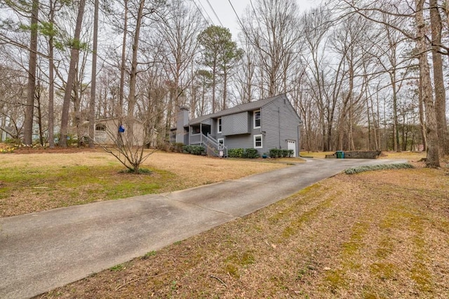 view of front of property with driveway, a chimney, and a front yard