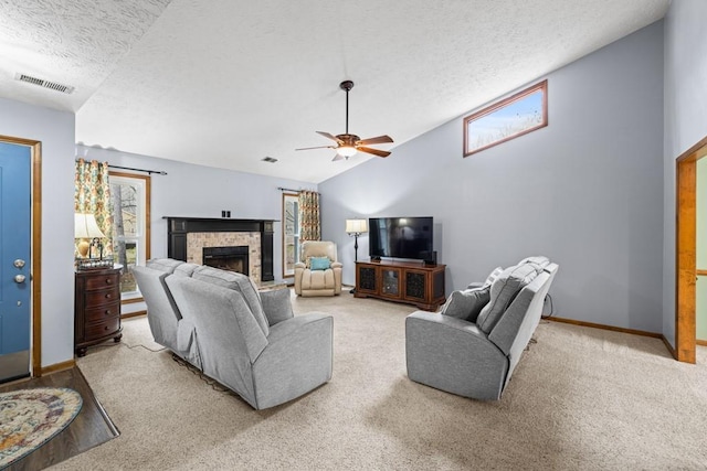 living area featuring a textured ceiling, light colored carpet, a fireplace, visible vents, and vaulted ceiling