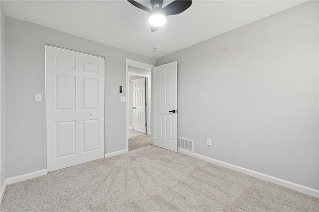 unfurnished bedroom featuring a closet, ceiling fan, and light colored carpet