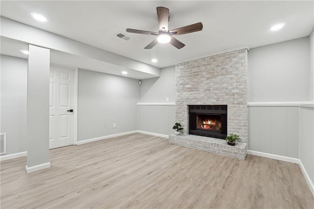 unfurnished living room featuring ceiling fan, light wood-type flooring, and a brick fireplace