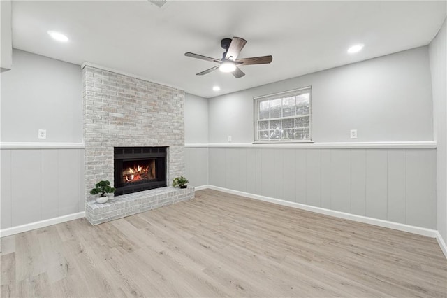 unfurnished living room with a fireplace, light hardwood / wood-style flooring, and ceiling fan