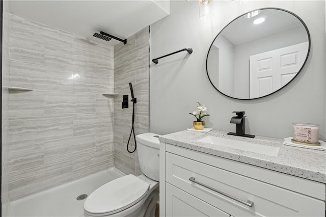 bathroom with tiled shower, vanity, and toilet