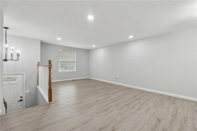 unfurnished living room featuring light wood-type flooring and an inviting chandelier