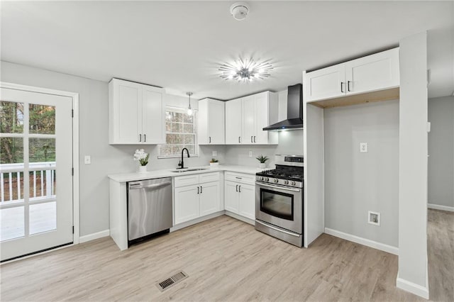 kitchen featuring wall chimney exhaust hood, white cabinetry, and appliances with stainless steel finishes