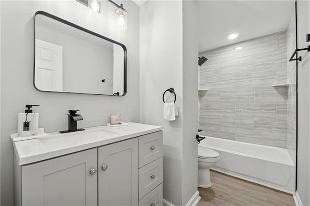 full bathroom featuring hardwood / wood-style flooring, vanity, toilet, and tiled shower / bath