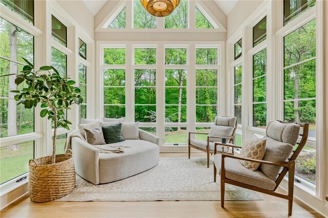 sunroom / solarium featuring wood finished floors and high vaulted ceiling