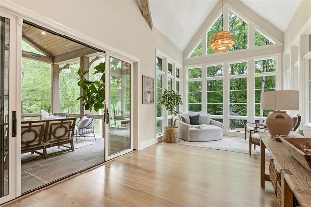 sunroom featuring wood finished floors, a wealth of natural light, and beamed ceiling