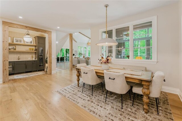 dining space with recessed lighting, baseboards, indoor bar, and light wood finished floors