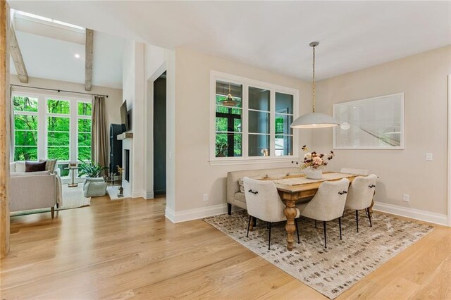 dining room with baseboards, wood finished floors, and beam ceiling