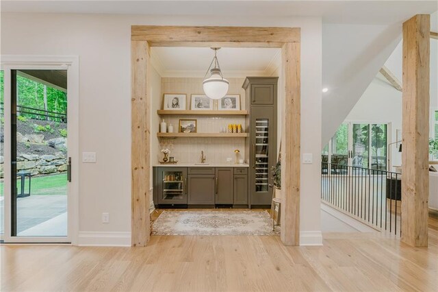 bar featuring baseboards, a dry bar, light wood-style flooring, and decorative backsplash