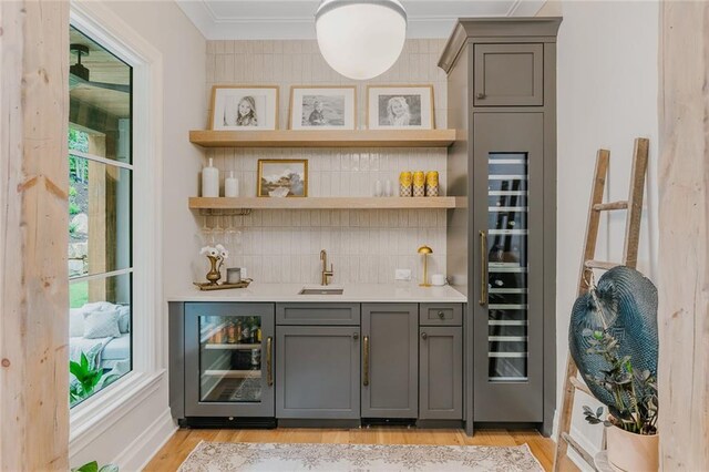 bar featuring indoor wet bar, beverage cooler, decorative backsplash, and a sink