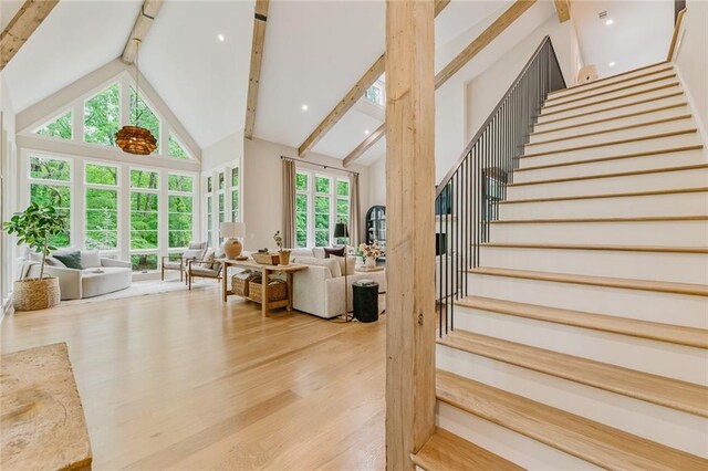 staircase featuring wood finished floors, high vaulted ceiling, and beamed ceiling