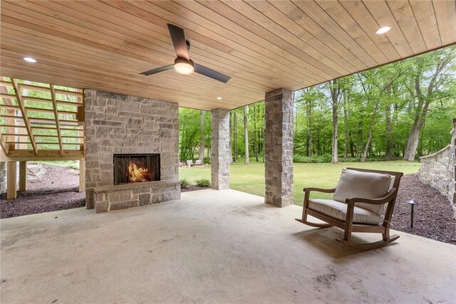 view of patio featuring an outdoor stone fireplace and ceiling fan