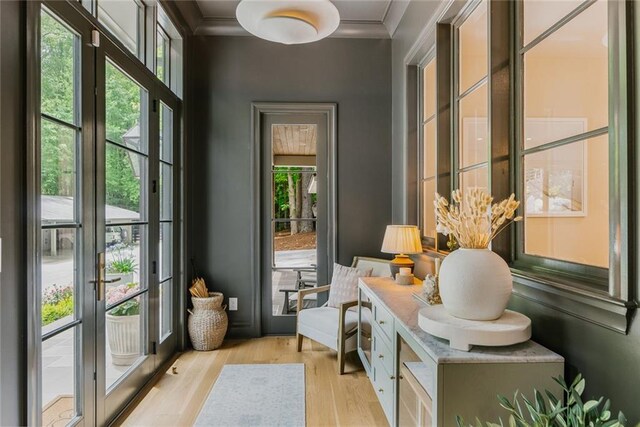 interior space featuring french doors, ornamental molding, and light wood finished floors