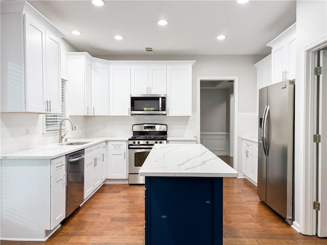 kitchen with light wood finished floors, a sink, visible vents, and stainless steel appliances