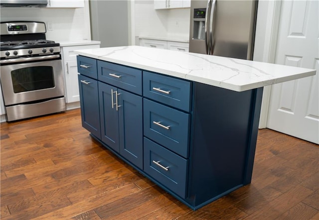 kitchen featuring light stone counters, white cabinetry, blue cabinetry, dark wood finished floors, and stainless steel appliances