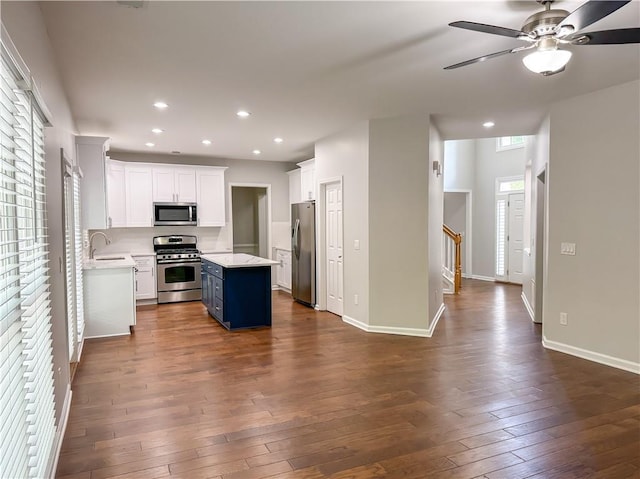 kitchen with dark wood finished floors, white cabinets, appliances with stainless steel finishes, light countertops, and a sink
