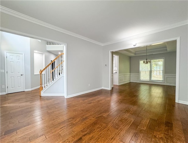 spare room with an inviting chandelier, ornamental molding, and hardwood / wood-style flooring