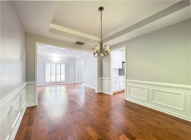 unfurnished dining area with crown molding, a tray ceiling, visible vents, a chandelier, and dark wood-style flooring
