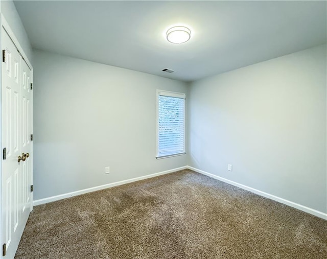 unfurnished room with visible vents, baseboards, and dark colored carpet
